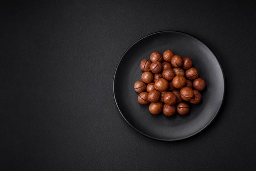 Delicious roasted macadamia nuts in shell on a dark textured background photo