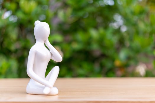 Ceramic Yoga Figurine of Woman doing yoga pose on wooden floor and green leaf  background photo