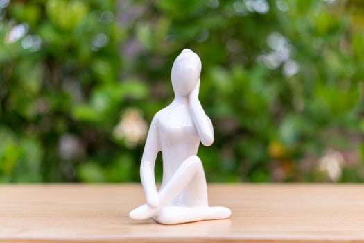 Ceramic Yoga Figurine of Woman doing yoga pose on wooden floor and green leaf  background photo