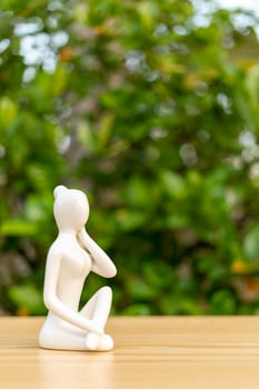 Ceramic Yoga Figurine of Woman doing yoga pose on wooden floor and green leaf  background photo