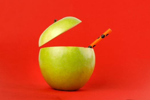 Healthy Green Cut Apple recyclable paper straw juice drink idea concept on red background photo