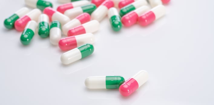 Capsules pill spread on white background. Prescription drugs. Capsule pill production. Green, pink, and white color capsule pills. Pharmaceutical industry. Medication and pharmacology. Health care. photo