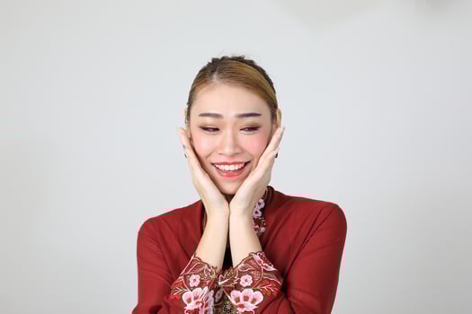 Asian woman traditional red maroon kebaya sharong on white background happy smile surprised hand on cheek photo