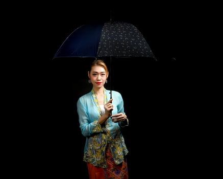 Asian woman in tractional kebaya carrying umbrella on black background photo