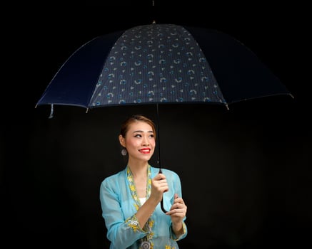 Asian woman in tractional kebaya carrying umbrella on black background photo