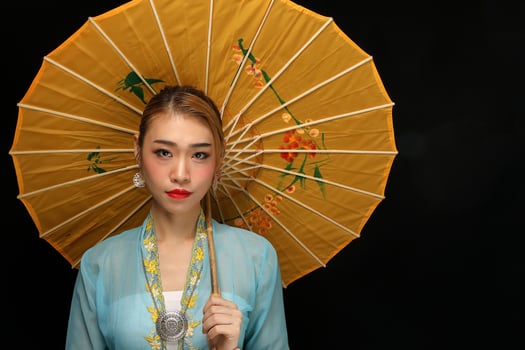 Asian woman in tractional kebaya behind umbrella on black background photo