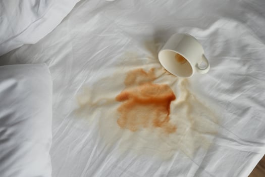 cup of coffee spilled white bed photo