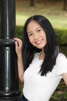 One Asian Chinese  woman posing smile look forward towards camera confident outdoor green park photo