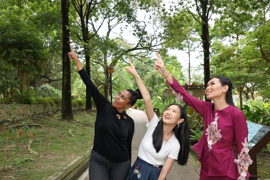 Three woman Malay Chinese Indian Asian outdoor green park  nature point finger up showing photo
