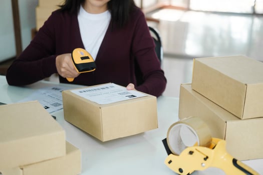 Female online business owner scan shipping label on parcel. photo