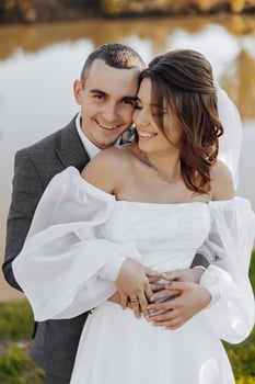 elegant beautiful couple. The groom embraces the bride. She lovingly leaned against him. Wonderful light adds to the romantic atmosphere. The bride and groom smile beautifully. photo