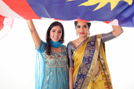 Two South east Asian Indian race ethnic origin woman wearing Indian dress costume sharee and salwar kameez multiracial community holding under Malaysian flag Jalur Gemilang on white background photo