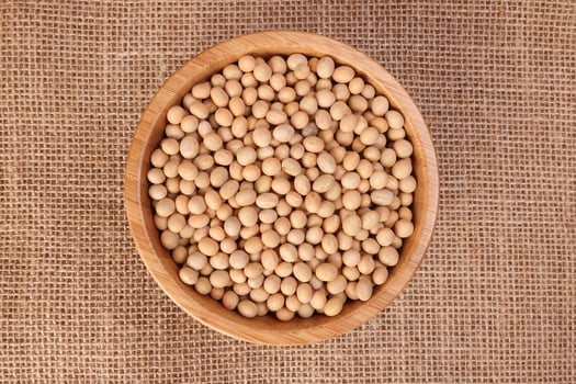 Soya bean in wooden bowl on jute yarn fabric background photo