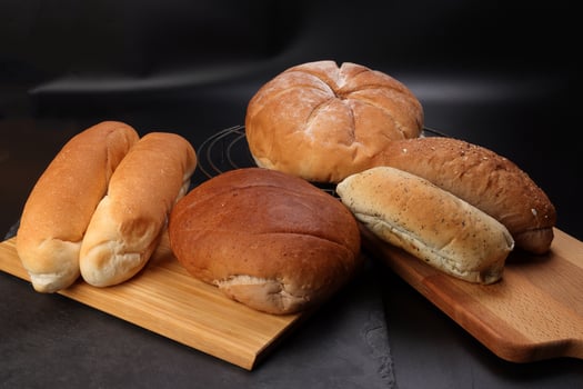 Freshly baked bread loaf bun roll round long mix verity on wooden board metal grill over black background photo