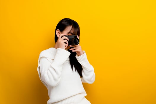 Female photographer with camera young women love taking pictures camera lover taking pictures in the yellow studio photo