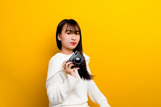 Female photographer with camera young women love taking pictures camera lover taking pictures in the yellow studio photo