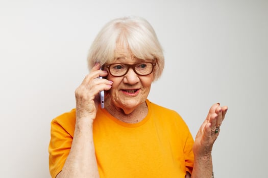 elderly woman in casual t-shirt sunglasses talking on the phone light background photo