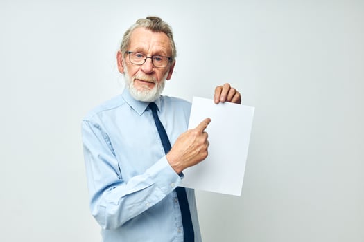 Senior grey-haired man holding documents with a sheet of paper light background photo