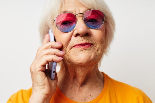 smiling elderly woman in casual t-shirt sunglasses talking on the phone close-up emotions photo
