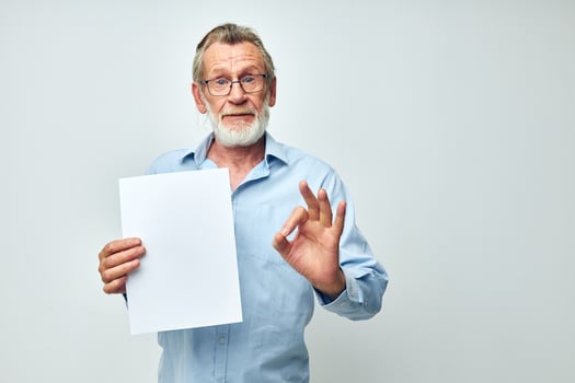 Senior grey-haired man holding a sheet of paper copy-space posing isolated background photo
