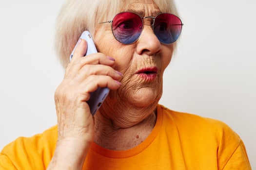 elderly woman in casual t-shirt sunglasses talking on the phone isolated background photo