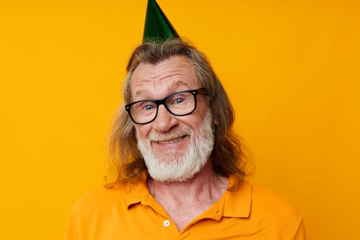 Senior grey-haired man fun birthday cap on the head isolated background photo