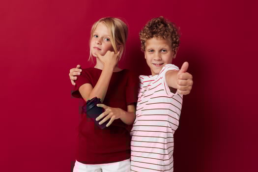 boy and girl disposable glass with drink posing red background photo