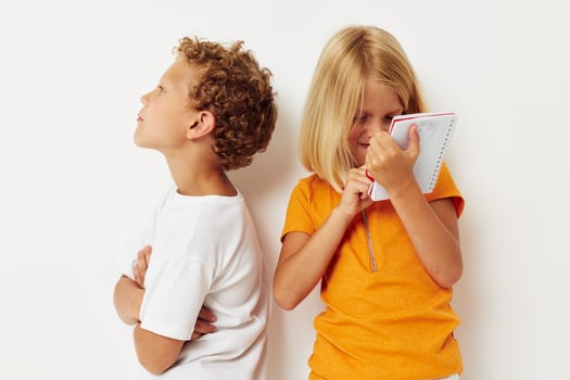 two joyful children stand next to notepad pencil drawing emotions lifestyle unaltered photo
