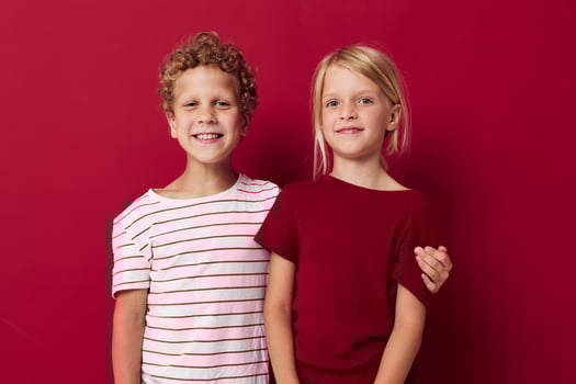 Small children good mood standing next to posing red background photo