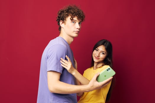 nice guy and girl in colorful T-shirts with a phone red background photo