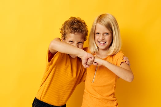 two joyful children in yellow t-shirts standing side by side childhood emotions yellow background photo