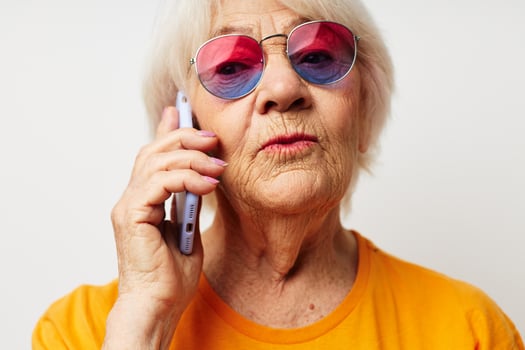 smiling elderly woman in casual t-shirt sunglasses talking on the phone close-up emotions photo