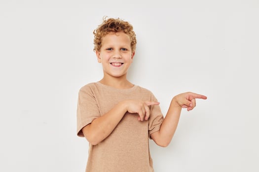 funny curly boy in a white t-shirt gestures with his hands photo