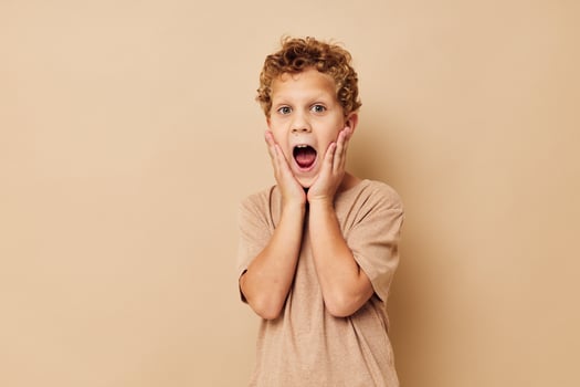 boy in a beige t-shirt with curly hair posing photo