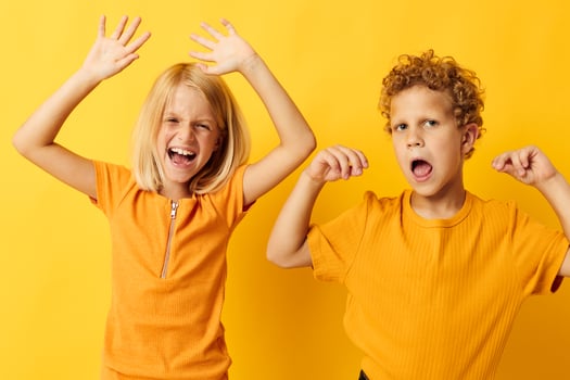 two joyful children casual wear games fun together posing on colored background photo
