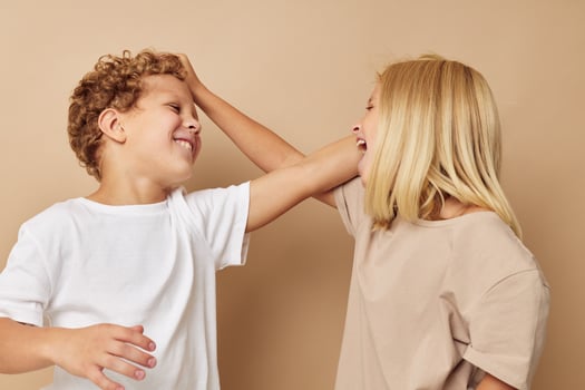 boy and girl holding each other by the hair beige background photo