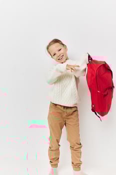 little girl school backpack with a hat on his head light background photo
