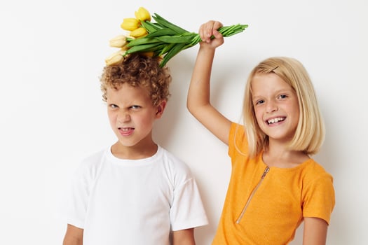 two joyful children with a bouquet of flowers gift birthday holiday childhood light background photo
