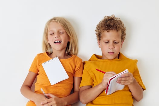 two joyful children lie on the floor with notepads and pencils childhood lifestyle unaltered photo