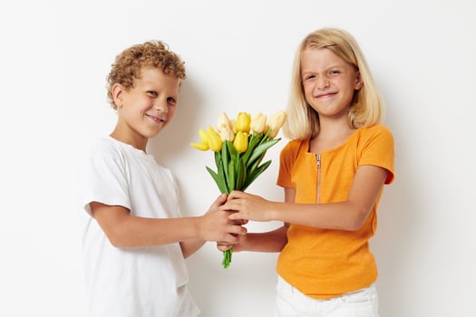 picture of positive boy and girl holiday friendship with a gift Yellow flowers light background photo
