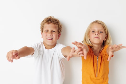 two joyful children posing hand gesture smile casual wear light background photo