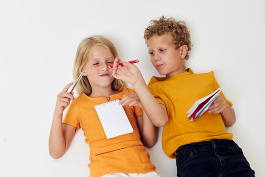 Small children lie on the floor with notepads and pencils isolated background unaltered photo