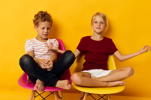 Small children childhood sitting on chairs together on colored background photo