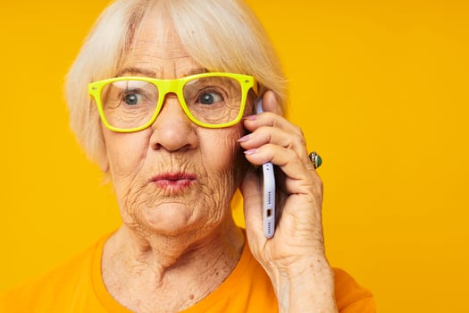 elderly woman talking on the phone in yellow glasses close-up emotions photo