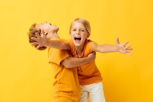 two joyful children cuddling fashion childhood entertainment on colored background unaltered photo