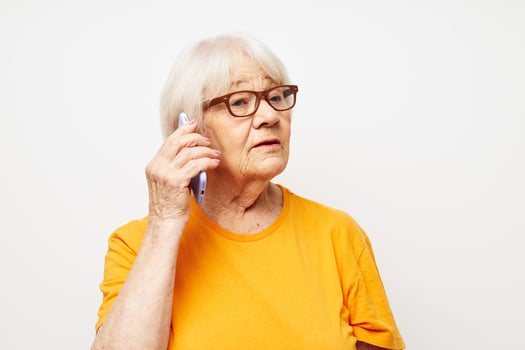 elderly woman in a yellow t-shirt posing communication by phone close-up emotions photo