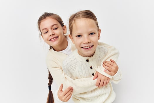 two little girls hug girlfriend light background photo