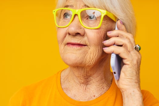 elderly woman talking on the phone in yellow glasses close-up emotions photo