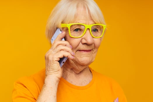 elderly woman talking on the phone in yellow glasses isolated background photo