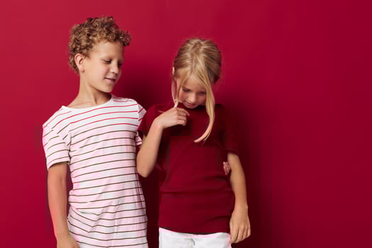Small children good mood standing next to posing red background photo